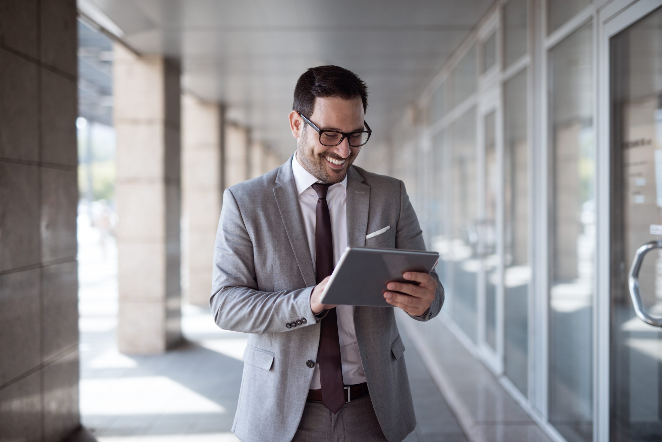 Businessman using tablet to check e-mail while standing in front of business center.